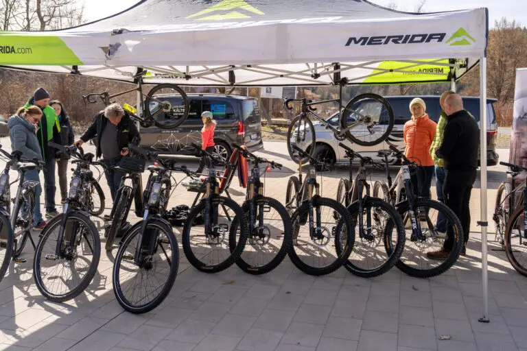 Manufacturers' test bikes under the tents, visitors talking in front of them