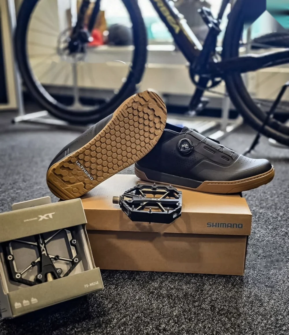 Der Shimano GF800 Trailschuh auf dem Karton, davor das XT Flatpedal in der Verpackung